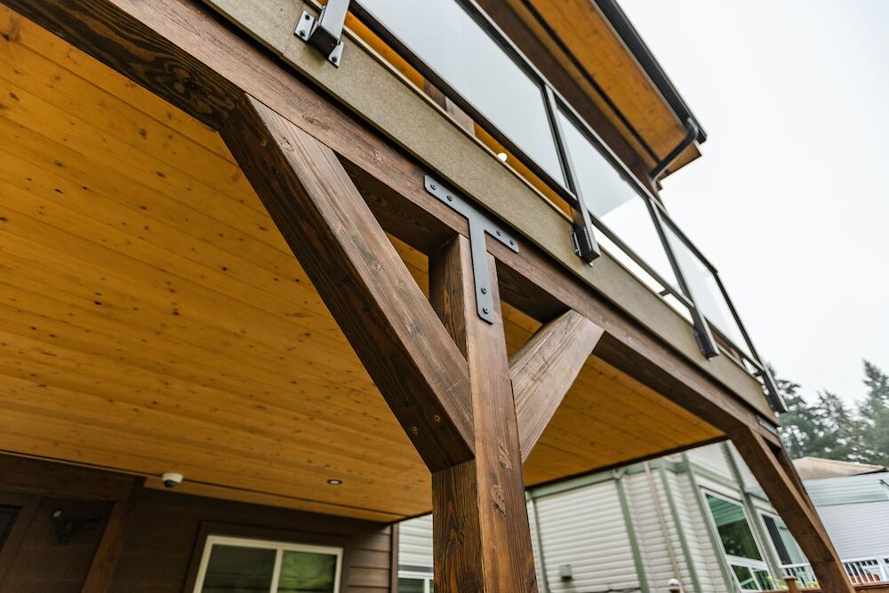 Heavy Douglas Fir timber post with custom steel bracing hardware supporting an elevated cedar deck