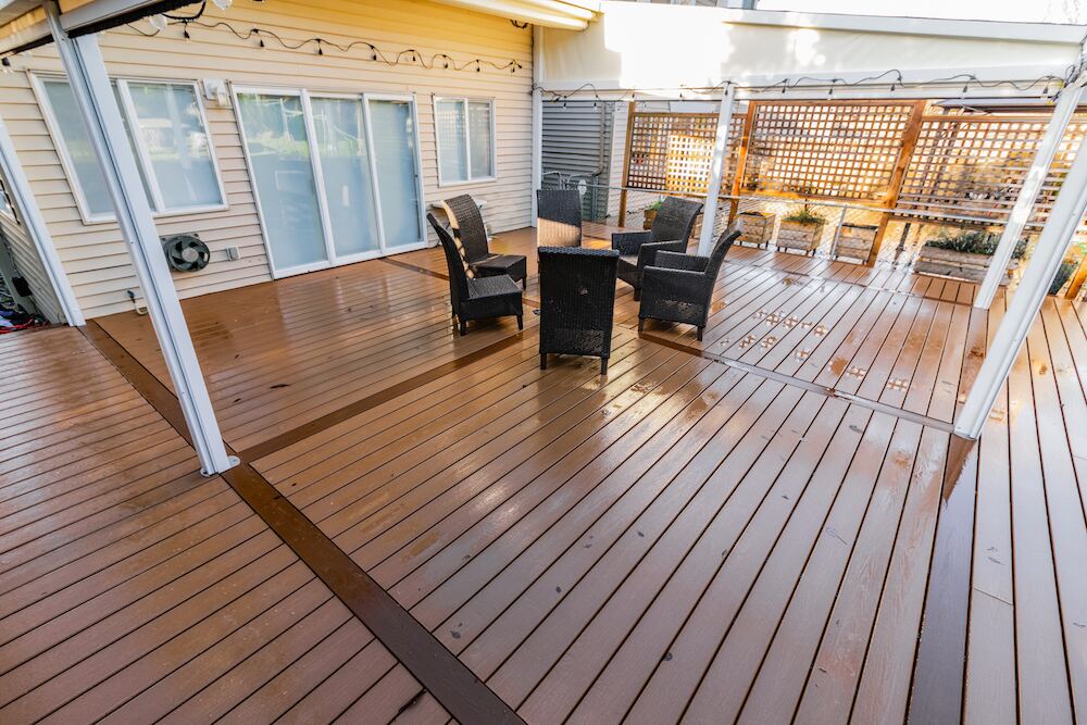 Covered composite deck with custom inlay pattern shedding rain, showing weather performance