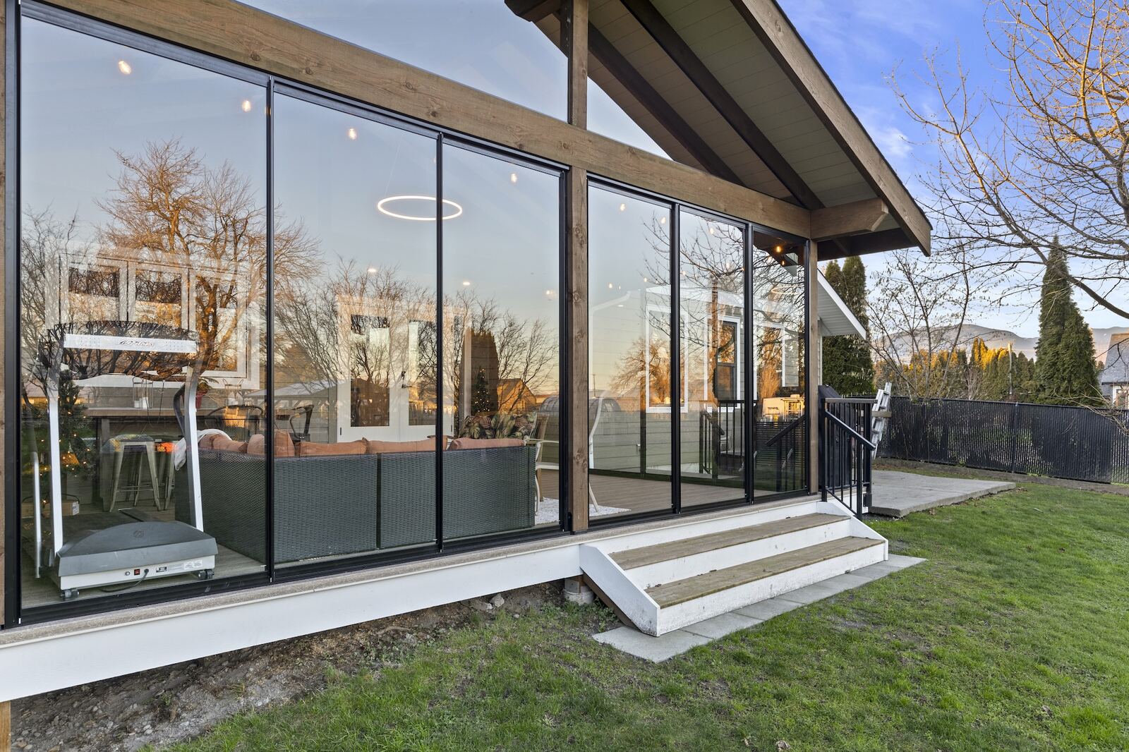 Cathedral-style sunroom with high vaulted ceiling, exposed timber framing, and a wall of black-framed glazing